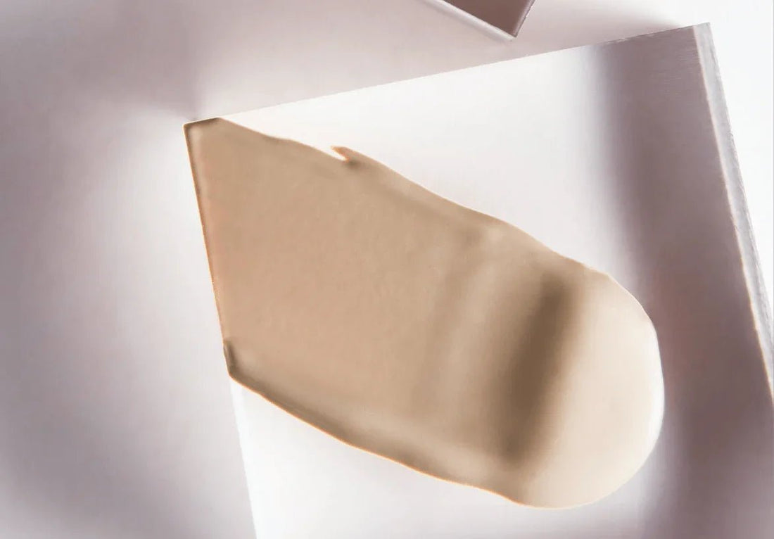 Beige swatch of tinted moisturizer on a white surface, creamy texture, makeup product