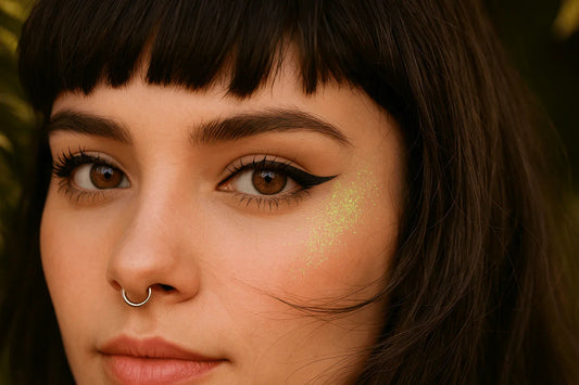 Woman with winged liquid eyeliner and green glitter on cheek, close-up beauty makeup look