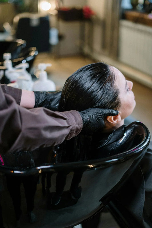 Professional salon hair washing with stylist in black gloves and wet hair care treatment