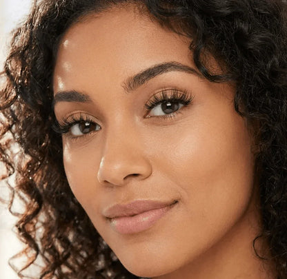 Woman with curly hair wearing natural wispy false eyelashes, close-up face view