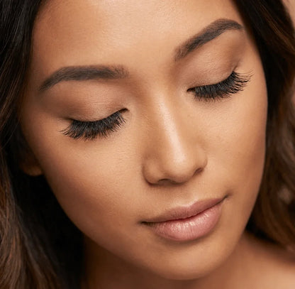 Woman wearing natural wispy false eyelashes, close-up with eyes closed, smooth makeup
