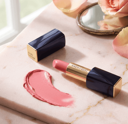 Pink lipstick with black and gold packaging on a marble surface with a swatch of pink color.