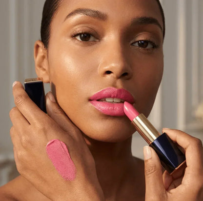 Woman applying pink lipstick with lipstick swatch on hand, beauty makeup closeup