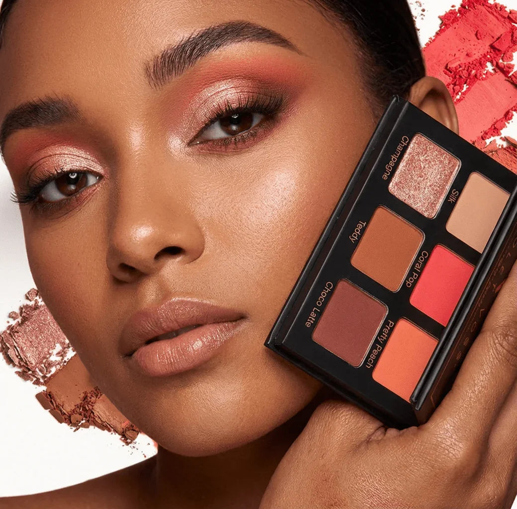 Woman with warm coral eyeshadow holding Violet Voss Coral Pop mini eyeshadow palette