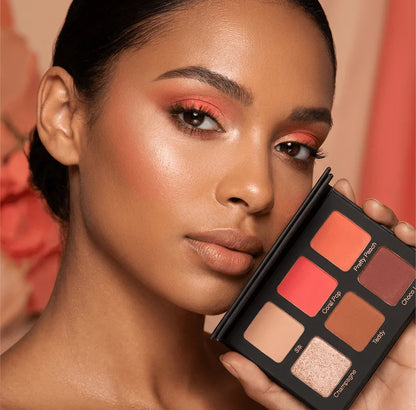 Close-up of woman with coral eyeshadow holding Violet Voss Coral Pop edition mini eyeshadow palette